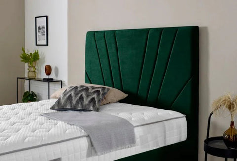 Green upholstered headboard in a bedroom setting with a bed and pillows.