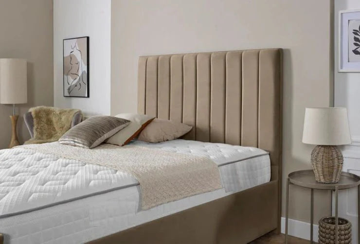 Beige upholstered bed with white bedding in a bedroom setting.