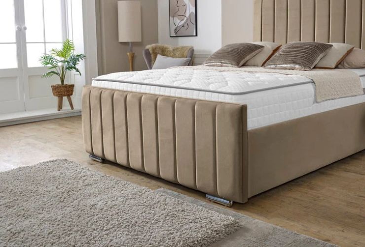Beige upholstered bed in a room with a window and plant