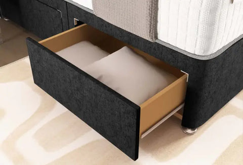 Bed with an open drawer revealing a mattress on a beige carpeted floor.
