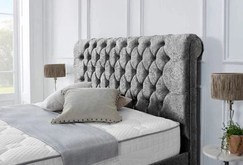 Gray tufted headboard on a bed with pillows and a blanket in a bedroom setting.