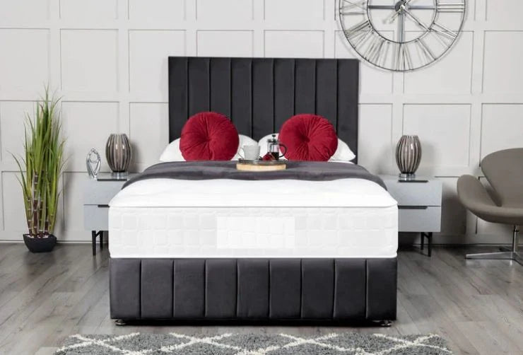 Bedroom with a black upholstered bed, white mattress, red pillows, and decorative items.