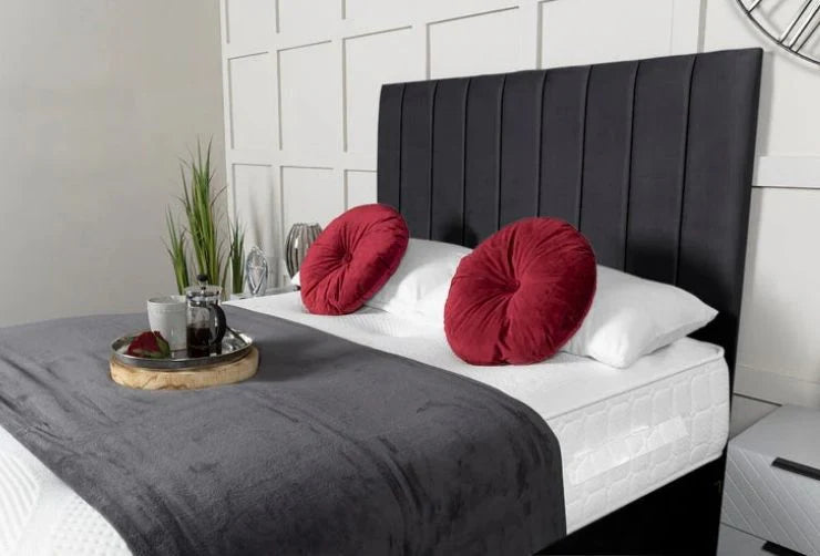 Bed with red pillows, gray blanket, and black headboard in a bedroom setting.