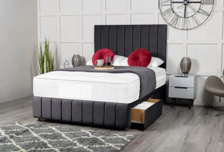 Gray upholstered bed with white mattress in a bedroom setting.