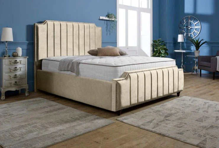 Beige upholstered bed in a room with blue walls, a window, and decorative items.
